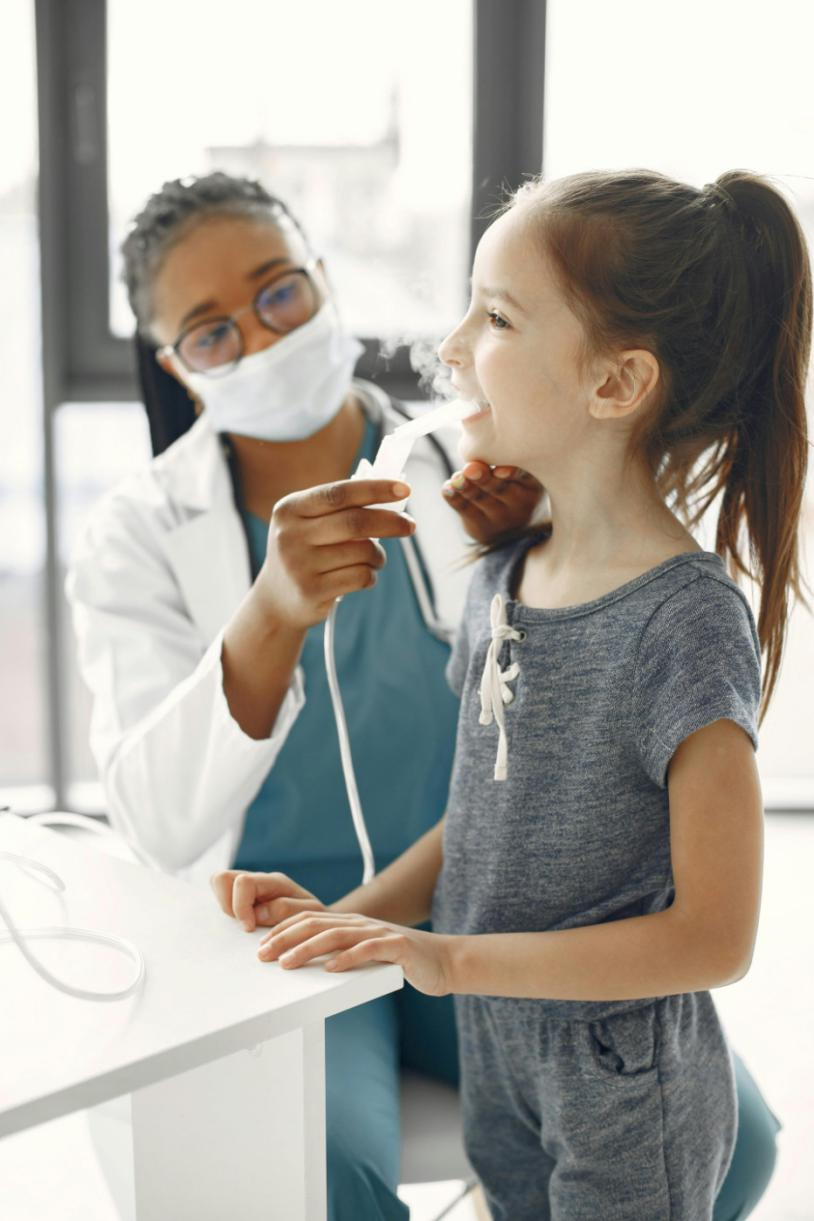 A doctor giving medication to a girl through a nebulizer 